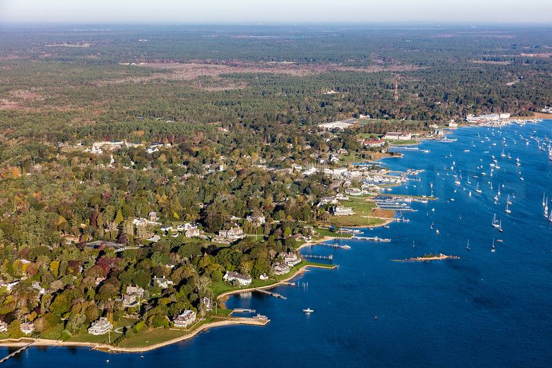 Aerial view of Marion's tree-lined village along sailboat-filled Sippican Harbor.