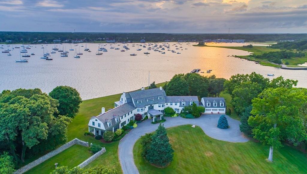 Aerial of a gambrel-roofed waterfront estate overlooking boat-filled Sippican Harbor in Marion.