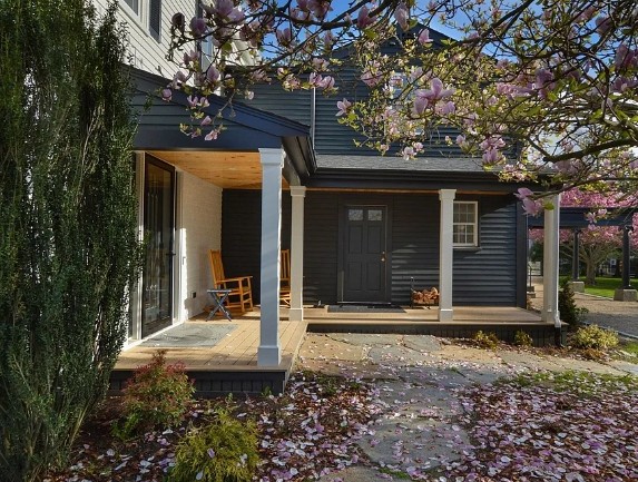 Navy-blue home with a white-columned farmer's porch framed by magnolia blossoms in New Bedford
