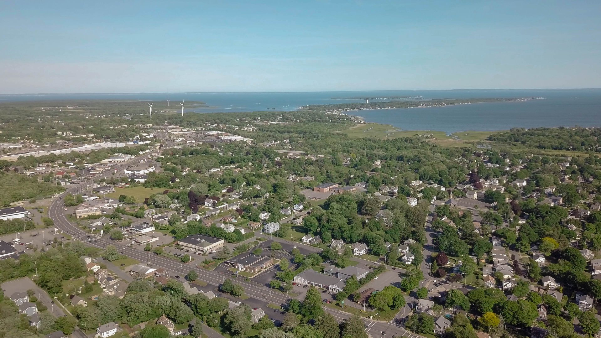 Drone view over Fairhaven showing Route 6, the town's wind turbines, and Buzzards Bay beyond.