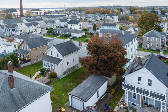 Aerial of a residential neighborhood with a brick mill smokestack in the distance in Fall River